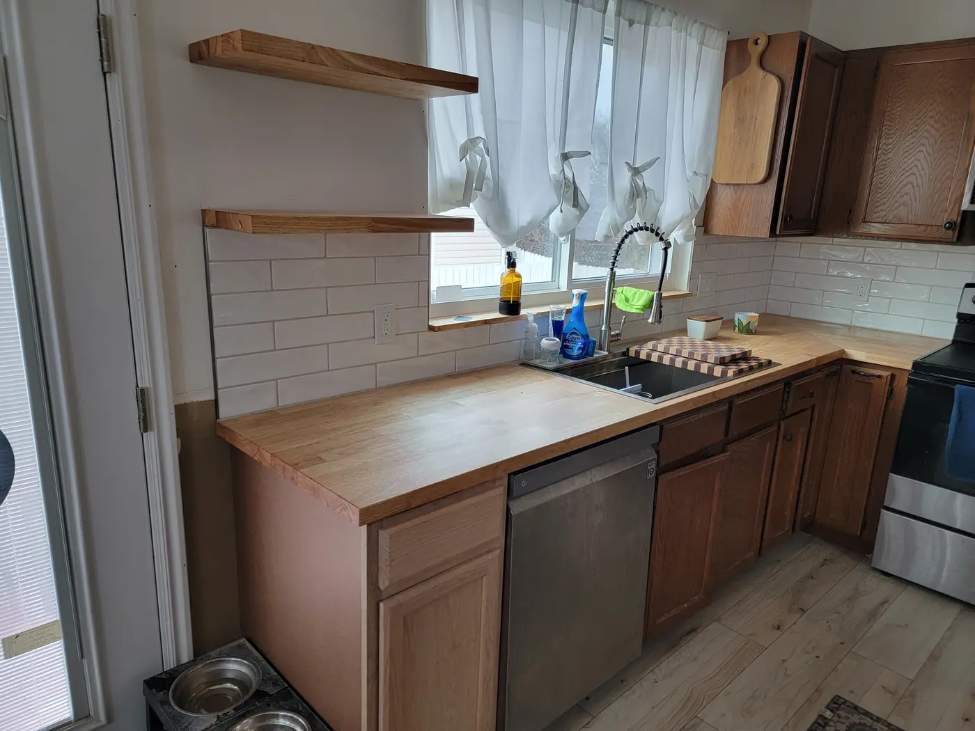 Finished kitchen — butcher block counters, white subway backsplash, floating shelves