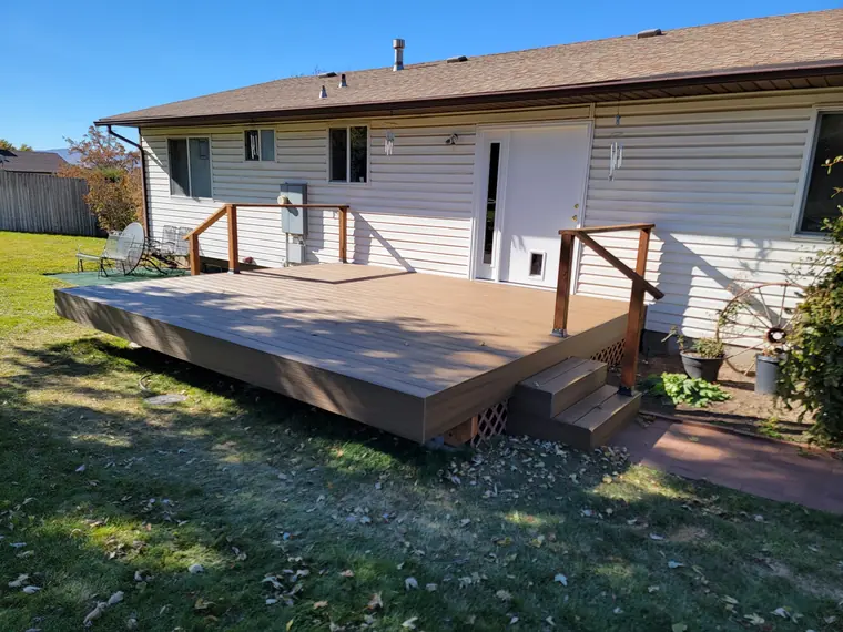 New composite deck with wood railing across the back of a house