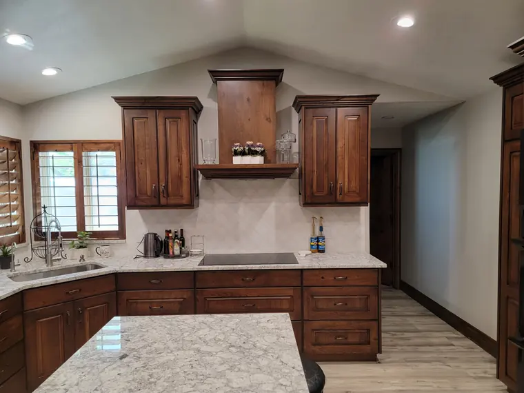 Finished kitchen with stained cabinetry and light granite counters