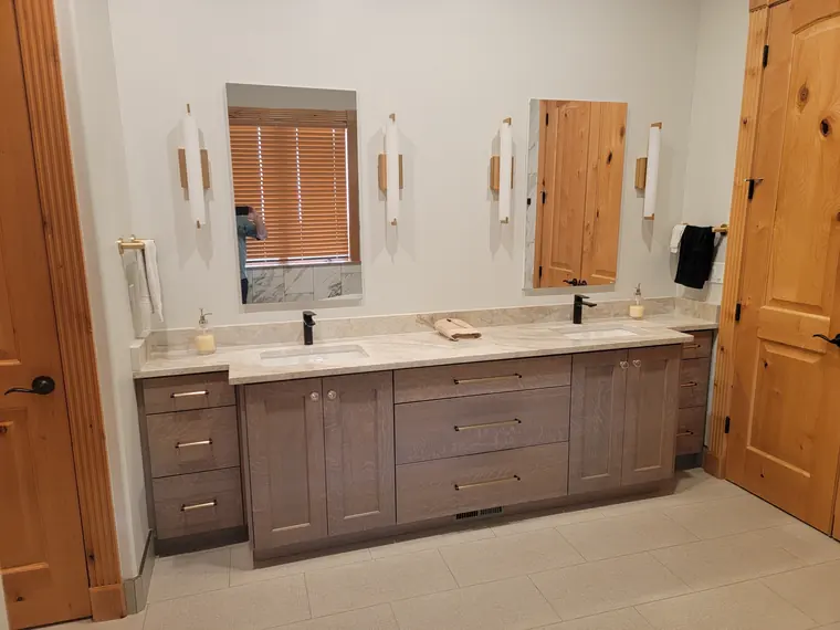 Finished primary bathroom with a double vanity and marble-look tile